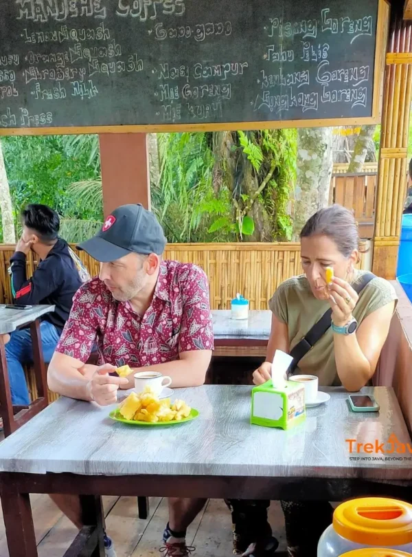 Two international travelers enjoying local coffee and traditional Banyuwangi snacks in East Java